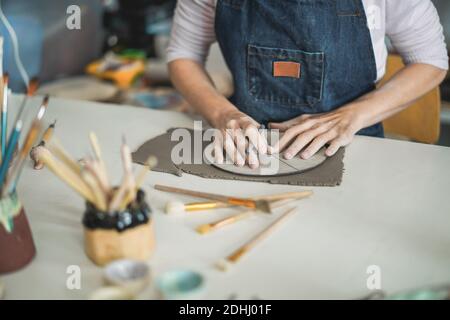 Donna che fa oggetti di ceramica all'interno di studio di ceramica creativa - Arte E workshop Concept - Focus on Hands Foto Stock