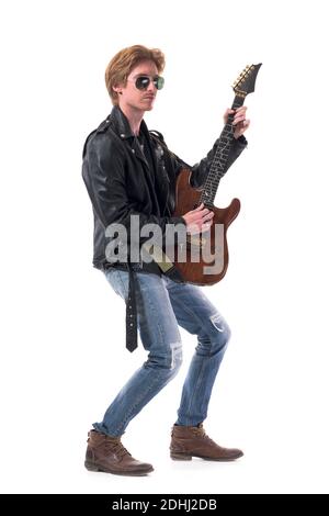 Vista laterale dell'elegante rocker con giacca in pelle che suona la chitarra elettrica indossando occhiali da sole. Lunghezza totale del corpo isolata su sfondo bianco. Foto Stock