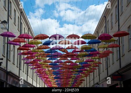 Ombrelli dai colori vivaci sospesi in una via di transito in città Di Bath nel Somerset Inghilterra UK Foto Stock