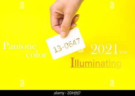 PANTONE colore dell'anno 2021. Biglietto da visita portatile con testo 13-0647, illuminante su sfondo giallo. Tendenza colore. Illuminazione Foto Stock