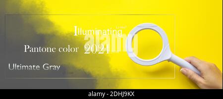 Pantone Color of the Year 2021. Lente di ingrandimento con mano sul giallo. Tendenza colore. Illuminazione. Ultimate Grey Foto Stock