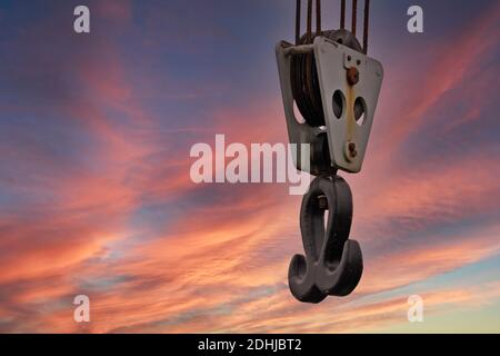 Gancio per gru appeso a cavi in acciaio con cielo tramonto sfondo Foto Stock