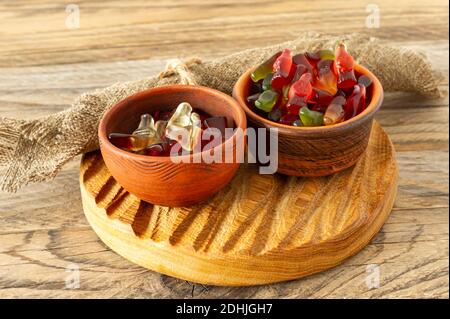 caramelle colorate e caramelle dolci, gelatina caramelle sapore frutta, dolci caramelle in ciotole di argilla in stile rustico vassoio di legno Foto Stock