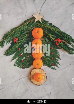 Natale e Capodanno con ramo thuja, caramelle, decorazioni e tangerini. Disposizione piatta, vista dall'alto. Foto Stock