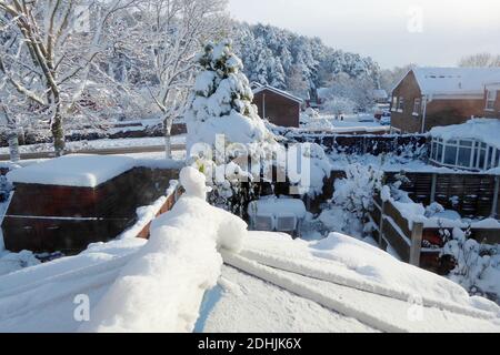 primo piano di neve coperto tetto serra, attraverso finestra. tetti e alberi con neve profonda deriva fuori in inverno Foto Stock