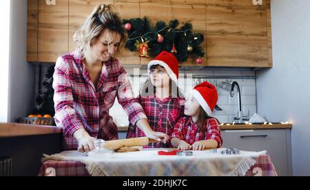 mamma insegna alle sue figlie in cucina a fare un delizioso dessert di pasta. Foto Stock