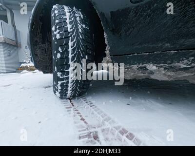 Pneumatici auto su una strada invernale innevata con piste. Foto Stock