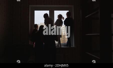 Silhouette di una grande famiglia sullo sfondo di una finestra in un nuovo appartamento. Foto Stock