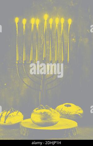 Festa ebraica Hanukkah sfondo con menorah tradizionale candelabro con candele e ciambelle brucianti, colore di tendenza di 2021. Foto Stock