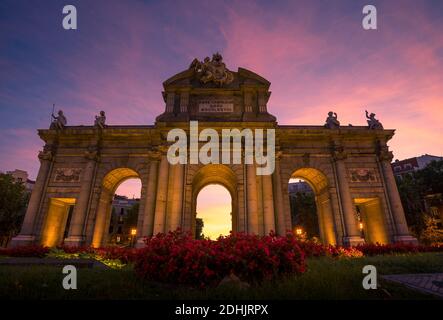 Dal basso della porta illuminata di Alcala situata a Madrid contro incredibile cielo al tramonto Foto Stock