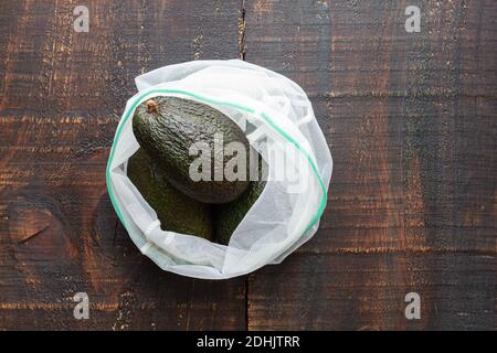 Dall'alto fresco verde avocado intero sul sacco posto tavolo rustico in legno Foto Stock