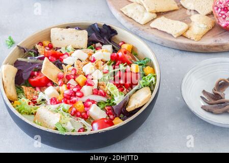 Da sopra ciotola di Caesar insalata con miscela verde condita con formaggio e pomodori con semi di melograno e cracker Foto Stock