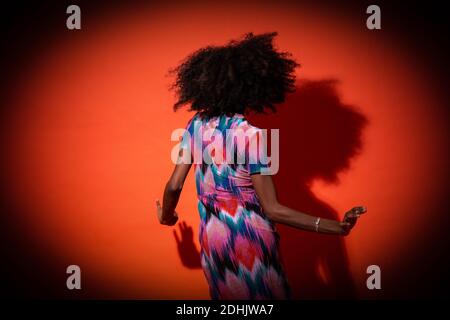 Vista posteriore Donna nera con acconciatura afro vestito vivace su sfondo rosso Foto Stock