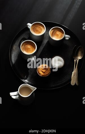 Tazze di caffè servite su un vassoio su sfondo scuro Foto Stock