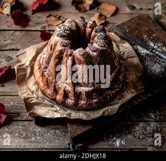 Dall'alto fresco gustoso Kugelhopf sul tavolo di legno stagionato vicino foglie di autunno asciutte Foto Stock