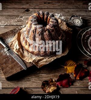 Dall'alto fresco gustoso Kugelhopf sul tavolo di legno stagionato vicino foglie di autunno asciutte Foto Stock