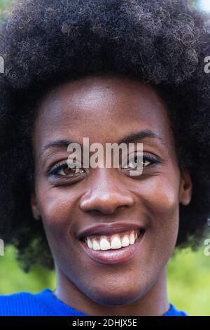 Allegra donna nera con acconciatura afro e affascinante sorriso togoloso guardando la fotocamera Foto Stock