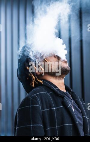 Medico maschio che mette su protezione di plastica viso mentre si lavora in clinica e guardando via Foto Stock
