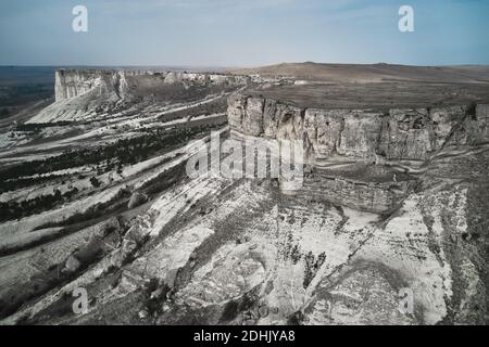 Da sopra drone vista di massiccia e ruvida formazione di pietra grigia situato tra la vasta valle montagnosa Foto Stock