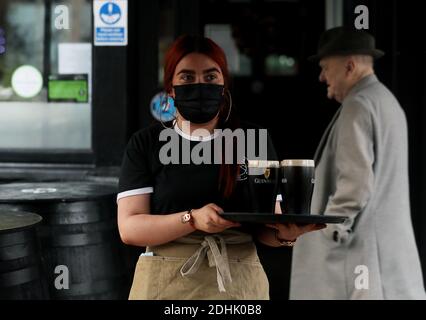 Dubheasa Courtney, cameriera del Mourne Seafood Bar nel centro di Belfast, si prepara a servire i clienti mentre le aziende dell'Irlanda del Nord riaprono le loro porte dopo un blocco di due settimane con interruttore automatico volto a arginare la diffusione del coronavirus. Foto Stock