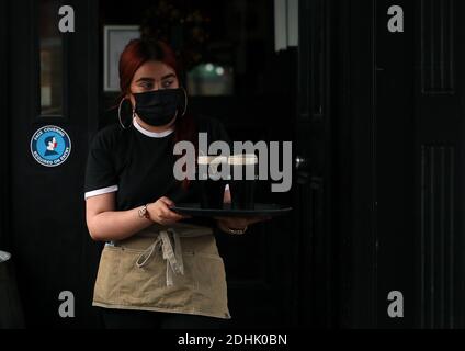 Dubheasa Courtney, cameriera del Mourne Seafood Bar nel centro di Belfast, si prepara a servire i clienti mentre le aziende dell'Irlanda del Nord riaprono le loro porte dopo un blocco di due settimane con interruttore automatico volto a arginare la diffusione del coronavirus. Foto Stock