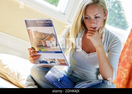 Giovane donna guardando indicazioni per case e appartamenti Foto Stock