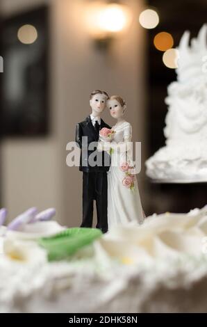 Figurine della sposa e dello sposo sulla torta di nozze. Con sfondo sfocato e bokeh Foto Stock