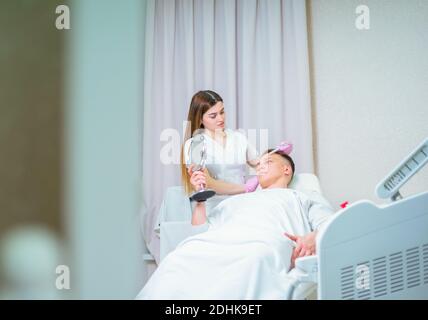 Cosmetici maschili. Un uomo dall'aspetto bello che riceve un trattamento viso presso una lussuosa spa Foto Stock