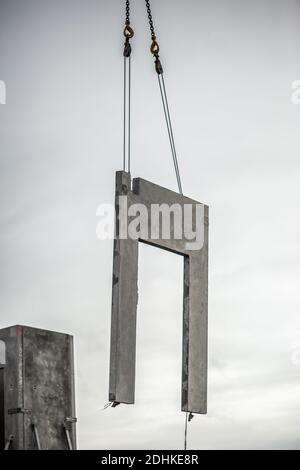 Una scala di grigi di una porta di cemento nell'aria sollevato da una gru Foto Stock