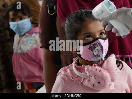 Mumbai, India. 11 Dicembre 2020. L'operatore sanitario controlla la temperatura di una ragazza durante lo screening.i passeggeri che viaggiano in treno dallo stato di Kutch, Rajasthan e Madhya Pradesh sono sottoposti a screening e, se si trova sospetto, devono sottoporsi a test con tampone presso i locali ferroviari. Credit: SOPA Images Limited/Alamy Live News Foto Stock