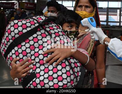 Mumbai, India. 11 Dicembre 2020. L'operatore sanitario controlla la temperatura di un ragazzo che trasporta un bagaglio durante lo screening.i passeggeri che viaggiano in treno dallo stato di Kutch, Rajasthan e Madhya Pradesh sono sottoposti a screening e, se si trova sospetto, devono sottoporsi a test con tampone presso i locali ferroviari. Credit: SOPA Images Limited/Alamy Live News Foto Stock