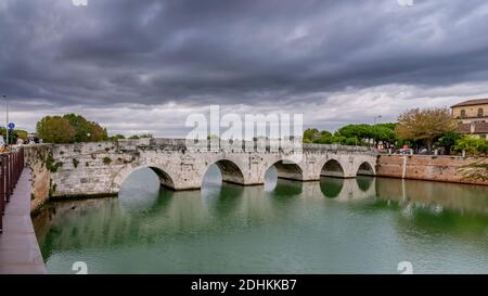 Vista sul Ponte di Tiberio o Ponte di Augusto, un ponte romano a Rimini, sotto un cielo suggestivo Foto Stock