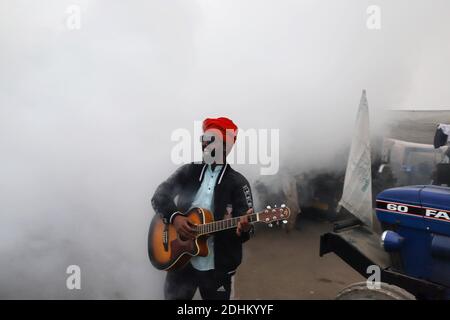 Nuova Delhi, Nuova Delhi, India. 11 Dicembre 2020. Un manifestante suona la chitarra in mezzo al fumo durante la fumigazione di un'area al confine di Singhu dove gli agricoltori sono accampati in una protesta continua contro le nuove leggi agricole del Centers il 11 dicembre 2020 vicino a Nuova Delhi, India. Credit: Vijay Pandey/ZUMA Wire/Alamy Live News Foto Stock