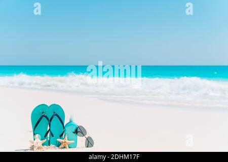 Bottiglie di crema solare, occhiali, stelle marine e occhiali da sole sulla spiaggia di sabbia bianca dell'oceano di sfondo Foto Stock