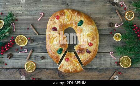 Roscón de Reyes su una base di legno con decorazioni natalizie. Spazio di copia. Tipico dessert dei tre Re in Spagna. Vista dall'alto. Foto Stock