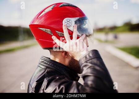 Guida sicura! Motociclista uomo in pelle nera giacca indossata su un casco. Foto Stock