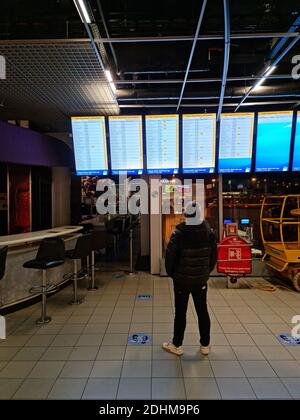 Uomo che guarda il bordo delle partenze dell'aeroporto Foto Stock