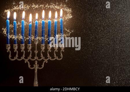 concetto di festa religiosa ebraica hanukkah con lampadario tradizionale menorah con pista di luce scintillante su sfondo nero scintillante Foto Stock