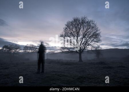 Una figura spettrale offuscata in campagna in una serata d'inverno dall'atmosfera struggente. Foto Stock