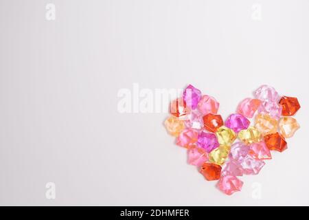 cuore di pietre di vetro multicolore su sfondo rosa. concetto di san valentino. alta qualità Foto Stock