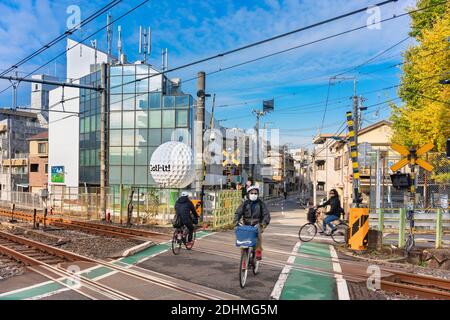 tokyo, giappone - dicembre 06 2020: Persone in bicicletta che passano oltre l'ultimo livello di attraversamento della linea Yamanote chiamata Nakazato Railroad Crossing II loca Foto Stock