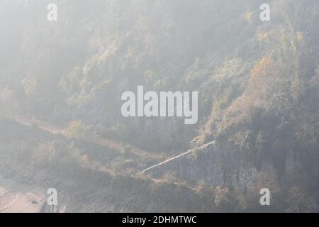 La nebbia sorge dagli alberi di Leigh Woods accanto alla linea di diramazione a singola pista della ferrovia Portishead e al fiume Avon a Bristol. Foto Stock