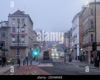 Il traffico scorre sulla ripida collina di Park Street a Bristol, dove il caratteristico Wills Memorial Building è avvolto dalla nebbia invernale. Foto Stock