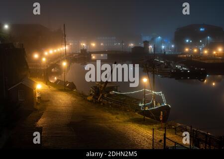 Le case galleggianti sono ormeggiate lungo le banchine di Bristol's Floating a Phoenix Wharf e Prince Street Bridge in una notte invernale nebbiosa. Foto Stock