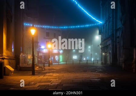 Le decorazioni natalizie sono avvolte nella nebbia in una notte invernale su Bristol's Corn Street. Foto Stock