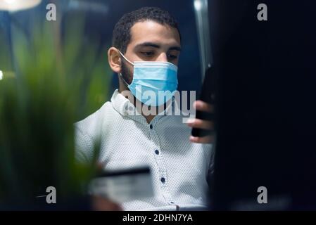 Uomo africano nero che tiene le mani carta di credito e telefono cellulare, il pagamento online durante la corona pandemic.Technology, internet banking, e-commerce healtcare Foto Stock