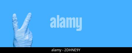 Guanto chirurgico con Gesture Victory. Segno V. Combattimento Covid-19. La mano con guanti mostra il numero due. Mano del medico che mostra 2 dita. Vittoria Foto Stock