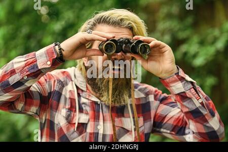 può vedere che. Concetto di viaggio. Guardare lontano in futuro. Hobby e relax. Turisti uomo con Binocolo alla ricerca di qualcosa lungo la foresta. Uomo con cannocchiale binocolo nella foresta. Foto Stock