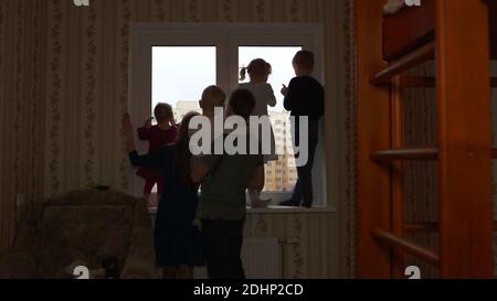 Silhouette di una grande famiglia sullo sfondo di una finestra in un nuovo appartamento. Foto Stock