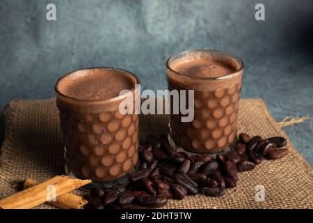 Tazze eleganti con cioccolata calda con fagioli di cacao intorno - cioccolata calda servita sul tavolo Foto Stock